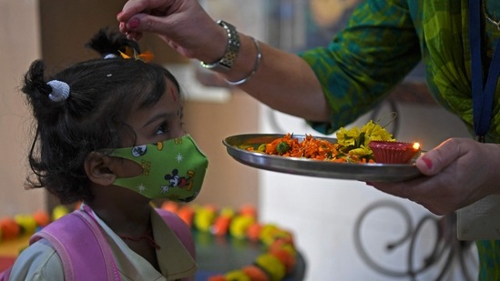 A teacher traditionally welcomes a student upon her arrival at a school in Mumbai on January 24.(AFP)