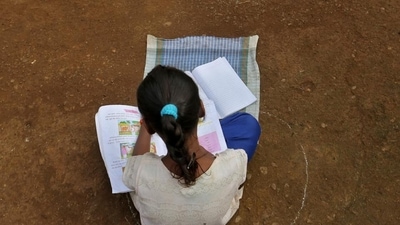 A girl, who missed her online classes due to lack of internet facilities, sits on the ground in a circle drawn with chalk to maintain safe distance as she listens to pre-recorded lessons over loudspeakers, after schools were closed due to Covid. (Reuters) A girl, who missed her online classes due to lack of internet facilities, sits on the ground in a circle drawn with chalk to maintain safe distance as she listens to pre-recorded lessons over loudspeakers, after schools were closed due to Covid. (Reuters)
