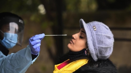 A health worker collects swab samples of a woman for Covid testing.