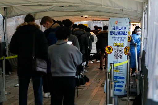 A medical worker moves to guide people as they wait for their coronavirus test at a makeshift testing site in Seoul, South Korea, Tuesday, Jan. 25, 2022. (AP)