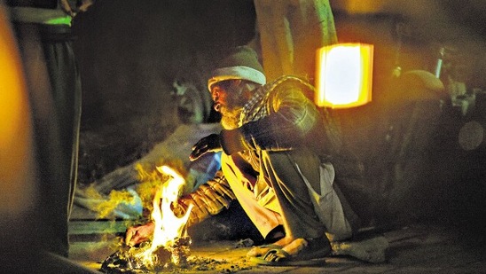 A man lights a fire to stay warm on a cold winter evening at south Delhi's Nizamuddin on Wednesday (Amal KS/HT Photo)