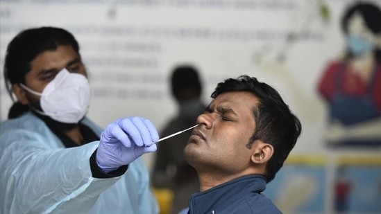 A health worker collects swab samples of a man for Covid-19 testing. (Vipin Kumar /HT)