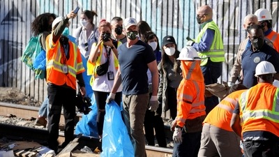 California Governor Gavin Newsom visits and helps clean the site where multiple train looting has occurred along the freight train tracks in Los Angeles. (Reuters)