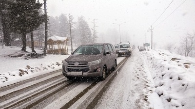 Vehicles ply on a snow-covered road as upper reaches of Jammu and Kashmir receives fresh snowfall. (ANI Photo)