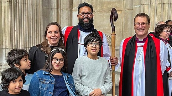 In this undated photo, Indian-origin Reverend Saju with his wife and children holding a staff made of Indian rosewood after a consecration ceremony at St. Paul's Cathedral in London. (PTI Photo) In this undated photo, Indian-origin Reverend Saju with his wife and children holding a staff made of Indian rosewood after a consecration ceremony at St. Paul's Cathedral in London. (PTI Photo)
