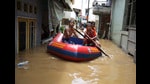 Youths use an inflatable raft to move through a flooded neighborhood in Jakarta, Indonesia, 2020 (AP)