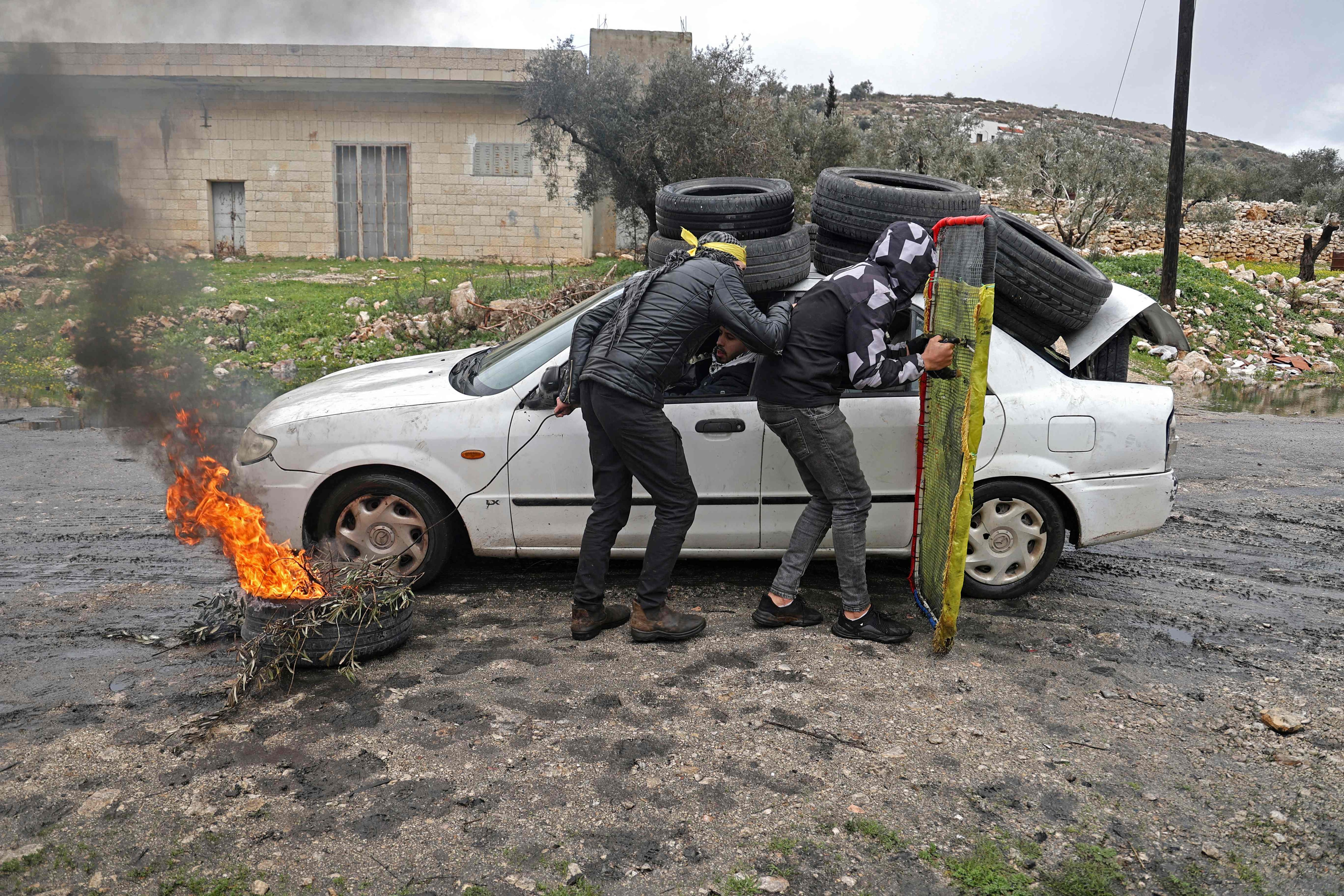 Palestinian protesters take cover during confrontations with Israeli security forces, in the village of Kfar Qaddum near the Jewish settlement of Kedumim in the occupied West Bank, on January 28, 2022. (AFP)