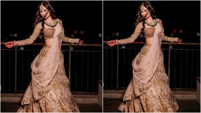 The lehenga comes adorned with intricate gold work and sheer nude panels placed aesthetically over the heavy ghera. Mouni completed her ensemble by draping a matching nude dupatta featuring matching gold patti borders and sequins on her shoulder. She wore it like a saree pallu. (Instagram/@imouniroy) The lehenga comes adorned with intricate gold work and sheer nude panels placed aesthetically over the heavy ghera. Mouni completed her ensemble by draping a matching nude dupatta featuring matching gold patti borders and sequins on her shoulder. She wore it like a saree pallu. (Instagram/@imouniroy)