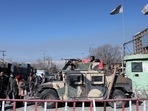 Afghans walk past a Humvee with a Taliban fighter on it guarding the road in Kabul, Afghanistan, January 27, 2022.