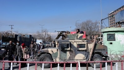 Afghans walk past a Humvee with a Taliban fighter on it guarding the road in Kabul, Afghanistan, January 27, 2022. (Reuters)