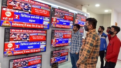 Employees at a showroom watch the live telecast of Finance Minister Nirmala Sitharaman's tabling of the Union Budget 2022-23 in the Lok Sabha, on TV sets in Bikaner, Tuesday. (PTI) Employees at a showroom watch the live telecast of Finance Minister Nirmala Sitharaman's tabling of the Union Budget 2022-23 in the Lok Sabha, on TV sets in Bikaner, Tuesday. (PTI)
