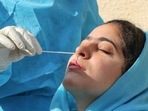 A healthcare worker collects a swab sample from a woman to test for Covid-19.(PTI)