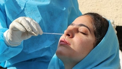A healthcare worker collects a swab sample from a woman to test for Covid-19. (PTI) A healthcare worker collects a swab sample from a woman to test for Covid-19. (PTI)