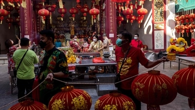 People hang Chinese lanterns while others light incense sticks at a shrine to mark the start of the Lunar New Year of the Tiger in Bangkok (Photo by Jack TAYLOR / AFP) People hang Chinese lanterns while others light incense sticks at a shrine to mark the start of the Lunar New Year of the Tiger in Bangkok (Photo by Jack TAYLOR / AFP)
