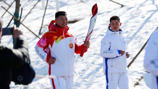 Torchbearer Qi Fabao, a regimental commander in the People's Liberation Army, relays the Olympic flame at the Winter Olympic Park.&nbsp;(Photo via REUTERS)