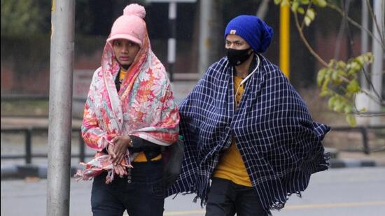 Women bundled in woollens near Sukhna Lake, Chandigarh, on a rainy Thursday morning. (Ravi Kumar/HT)