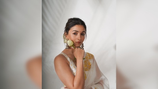 Tied her hair in a messy low middle-parted bun, Alia Bhatt pinned a fresh white rose to her bun for the classic vintage look.(Instagram/@aliaabhatt)