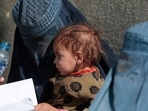&nbsp;A displaced Afghan woman holds her child as she waits with other women to receive aid supply outside a UNCHR distribution centre on the outskirts of Kabul, Afghanistan.