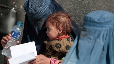 &nbsp;A displaced Afghan woman holds her child as she waits with other women to receive aid supply outside a UNCHR distribution centre on the outskirts of Kabul, Afghanistan. (REUTERS)