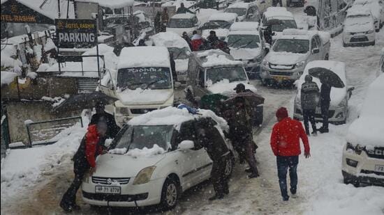 People clearing snow from their vehicles at a parking near old bus stand in Shimla on Friday. (Deepak Sansta /Hindustan Times)