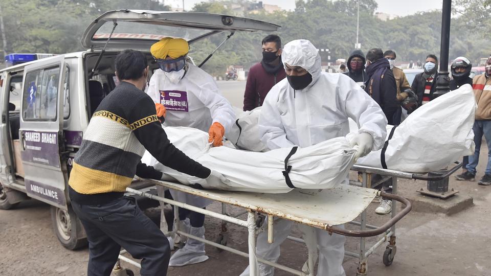Volunteers and relatives perform the last rites of a Covid-19 victim at the Seemapuri cremation ground in New Delhi. (Raj K Raj/HT File)
