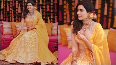 Karishma's bandhani print lehenga set comes with delicate marodi work and contrast red piping. It features a sleeveless blouse set with a deep U neckline, gold embroidery, mirror details, and a tassel-adorned back tie. She wore it with a matching lehenga skirt. (Instagram/@karishmaktanna)