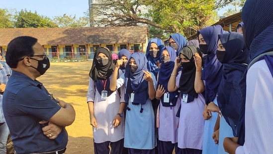 A faculty member talks with the students wearing hijab, after the school authorities denied them entry for wearing a hijab or scarf, in Kundapura of Udupi district.(PTI)