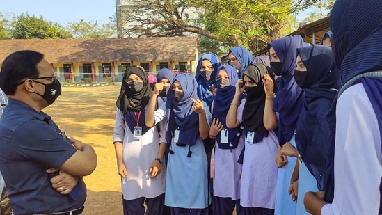 A faculty member talks with the students wearing hijab, after the school authorities denied them entry for wearing a hijab or scarf, in Kundapura of Udupi district, Saturday.(PTI)