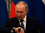 Russian President Vladimir Putin checks his watch before a press conference with French President Emmanuel Macron, in Moscow, Russia,