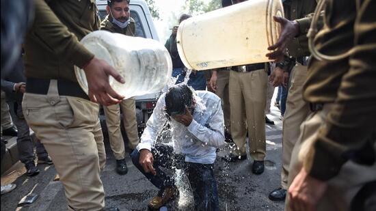 Delhi Police personnel pour water on a DU student who tried to immolate himself during the protest. (Sanchit Khanna/HT)