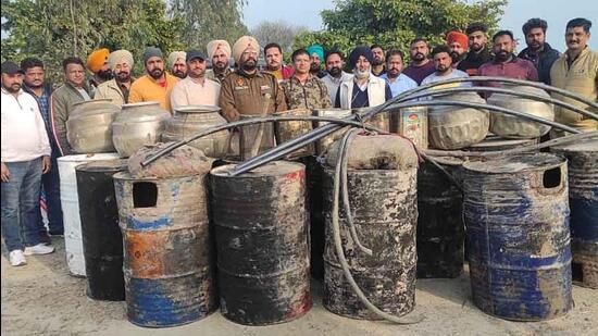 Excise department and police team with the recovered 95,000 litre lahan and 100 bottles of Illicit liquor near Khera Bet village in Ludhiana. (HT Photo)