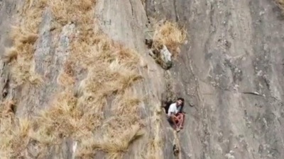 Kerala trekker R Babu is sitting in a small recess on the mountain face. (ANI Photo)