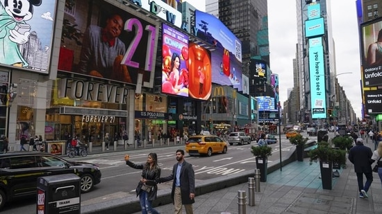 Pedestrians walk through Times Square while taking pictures in New York. Visitors again crowd below the jumbo screens in New York’s Times Square (AP)