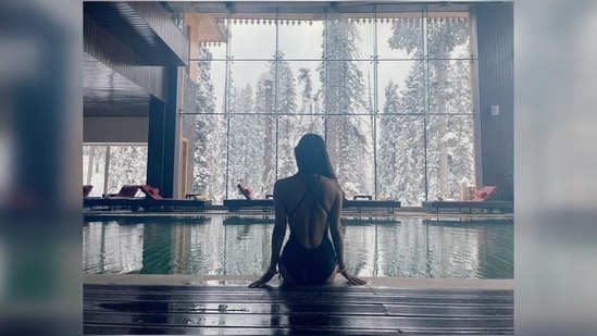 Mouni Roy dips her feet in the pool while striking a stunning pose for the camera with the snowcapped trees in the backdrop.(Instagram/@imouniroy)