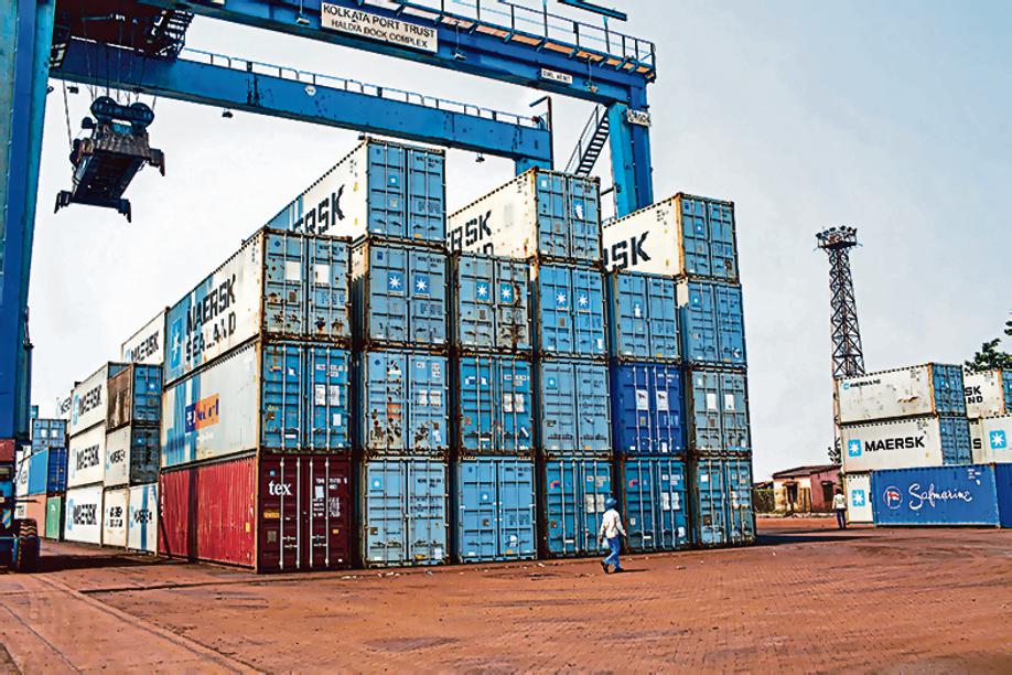 A worker walks past containers stacked under a gantry crane at the Haldia Dock Complex (HDC), part of the Kolkata Port Trust (KoPT), in Haldia, West Bengal, India, on Thursday, (Photographer: Sanjit Das/Bloomberg)