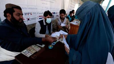 A displaced woman receives financial aid at a distribution centre on the outskirts of Kabul, Afghanistan. The US President Joe Biden has kicked off a complex process that could divide up the frozen assets of the Afghan central bank that are parked in the US amounting to $7 billion. (REUTERS) A displaced woman receives financial aid at a distribution centre on the outskirts of Kabul, Afghanistan. The US President Joe Biden has kicked off a complex process that could divide up the frozen assets of the Afghan central bank that are parked in the US amounting to $7 billion. (REUTERS)
