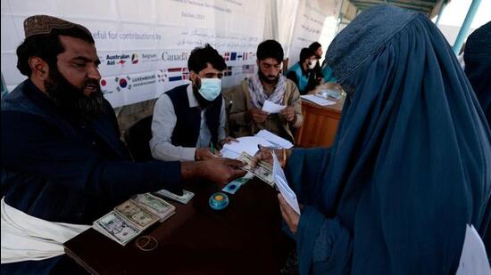 A displaced woman receives financial aid at a distribution centre on the outskirts of Kabul, Afghanistan. The US President Joe Biden has kicked off a complex process that could divide up the frozen assets of the Afghan central bank that are parked in the US amounting to $7 billion. (REUTERS)