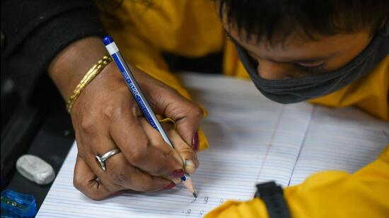 An instructor tends to a student during a cursive writing session at Likhavat Academy, in Kamla Nagar, New Delhi. (Amal KS/HT Photo)