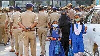 Students arrive to attend a school that re-opened after Karnataka High Court's interim order restrained students from wearing religious symbols inside the classroom, in Bengaluru on Monday. (PTI) Students arrive to attend a school that re-opened after Karnataka High Court's interim order restrained students from wearing religious symbols inside the classroom, in Bengaluru on Monday. (PTI)