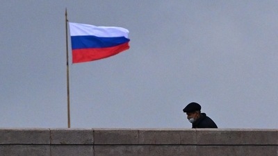 A pedestrian wearing a face mask walks past a Russian flag in Moscow. (Photo by Yuri KADOBNOV / AFP) A pedestrian wearing a face mask walks past a Russian flag in Moscow. (Photo by Yuri KADOBNOV / AFP)