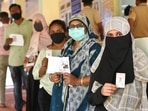 People holding their identification cards, stand in a queue to cast their votes in the Goa Assembly polls.