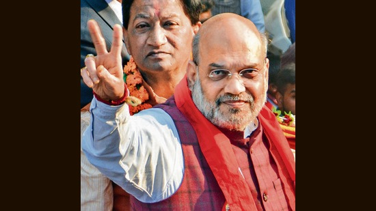Union Home Minister Amit Shah flashes the victory sign, during a roadshow for UP Assembly elections, in Sisamau, Kanpur. (PTI)