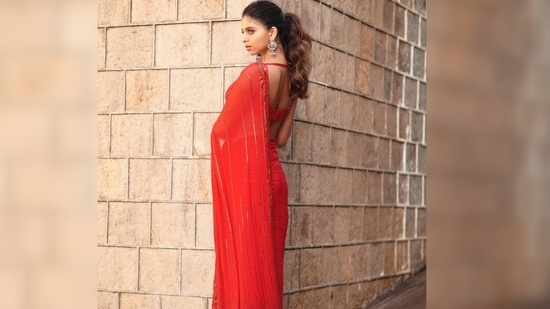 Suhana Khan paired her look with a sleeveless sequin red backless blouse and oxidised silver jhumkas. She opted for subtle makeup and tied her hair up in a ponytail.(Instagram/@manishmalhotra05)