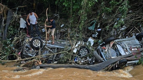 People try to rescue items from cars destroyed by a flash flood in Petropolis, Brazil on February 16, 2022. (Photo by CARL DE SOUZA/AFP)