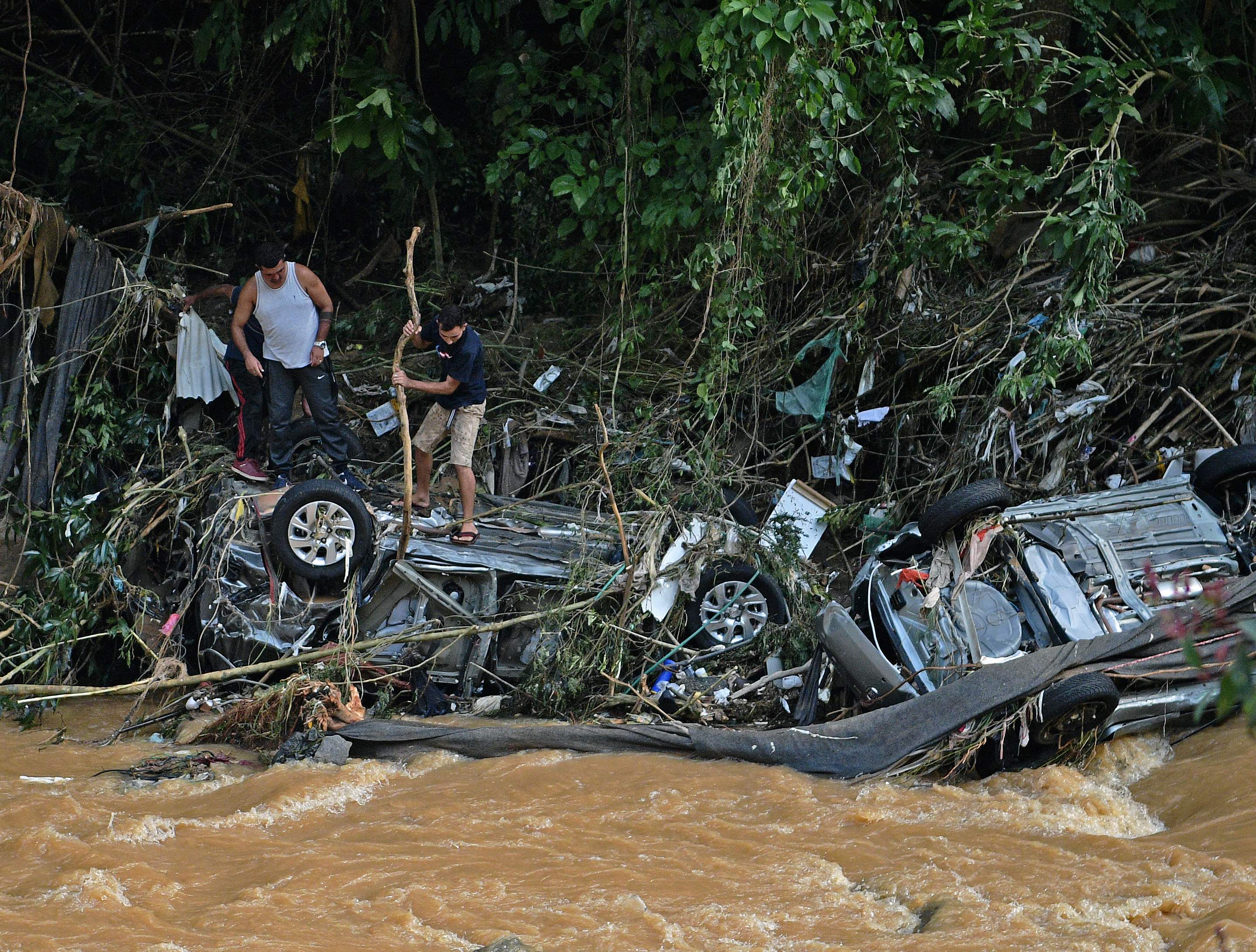 People try to rescue items from cars destroyed by a flash flood in Petropolis, Brazil on February 16, 2022. (Photo by CARL DE SOUZA/AFP) People try to rescue items from cars destroyed by a flash flood in Petropolis, Brazil on February 16, 2022. (Photo by CARL DE SOUZA/AFP)