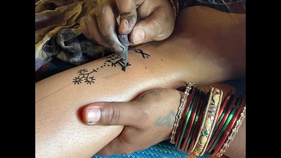 Tattoo artist Mangalabai of Madhya Pradesh’s Badni tribe at work. (Photo courtesy Shomil Shah)