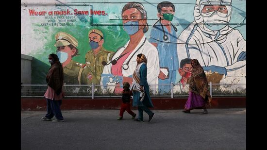 Women walk past a graffiti in New Delhi, February 7, 2022 (REUTERS)