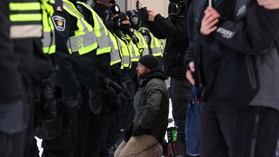 A demonstrator against Covid-19 mandates kneels in front of police in Ottawa on Friday. (AFP)