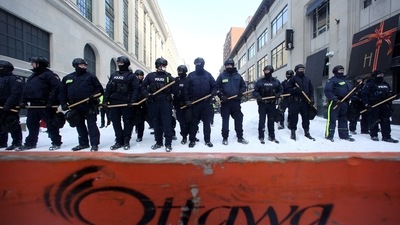 Canadian police officers stand guard and hold batons, as they work to restore normality to the capital while trucks and demonstrators continue to occupy the downtown core for more than three weeks to protest against pandemic restrictions in Ottawa. (REUTERS)