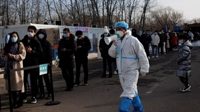 A staff member in a protective suit instructs people who are lining up for a throat swab test at a temporary Covid-19 testing center in Beijing, China. (Reuters / File)